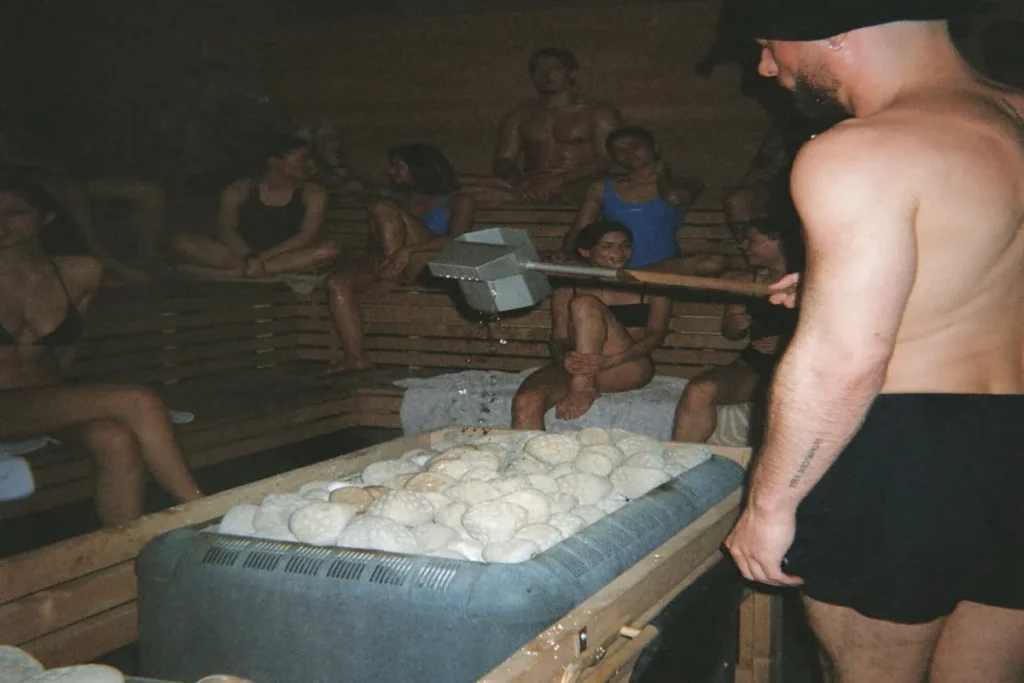 People sitting in a sauna practicing heat therapy and mindfulness for improved relaxation and wellness.